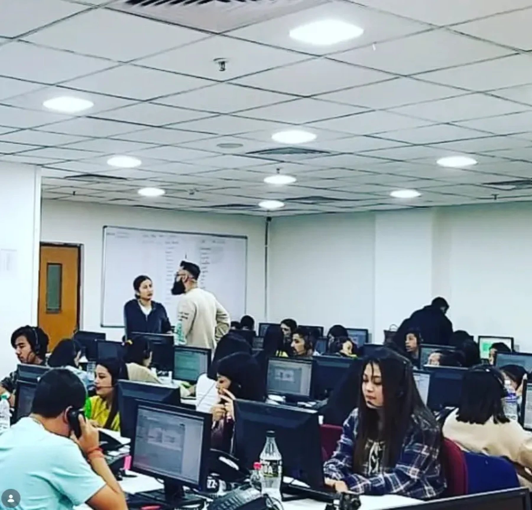RHI office operations floor with agents working at desktop computers and supervisors speaking nearby.