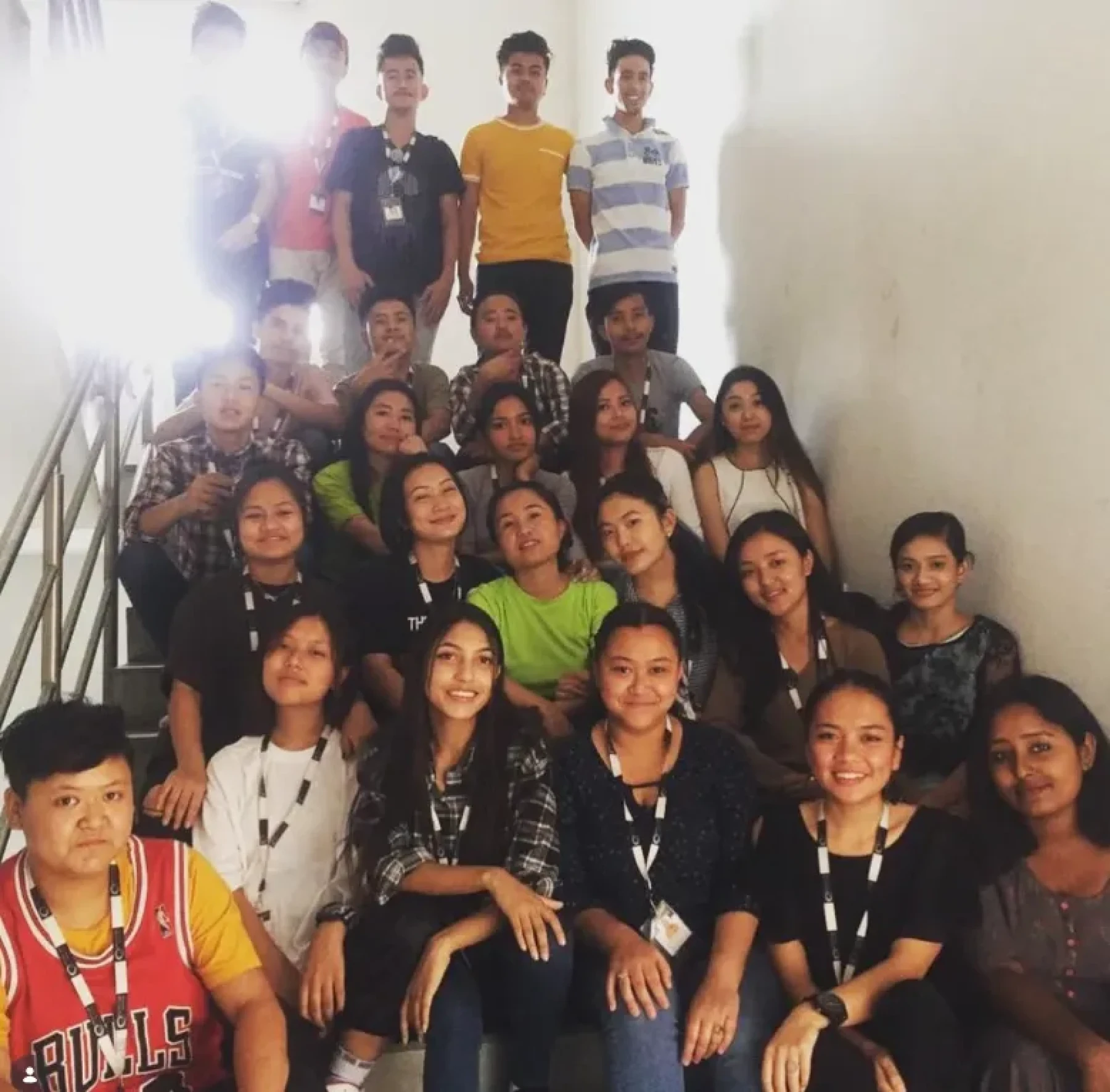 RHI team members wearing ID lanyards seated and standing together on an office stairwell.